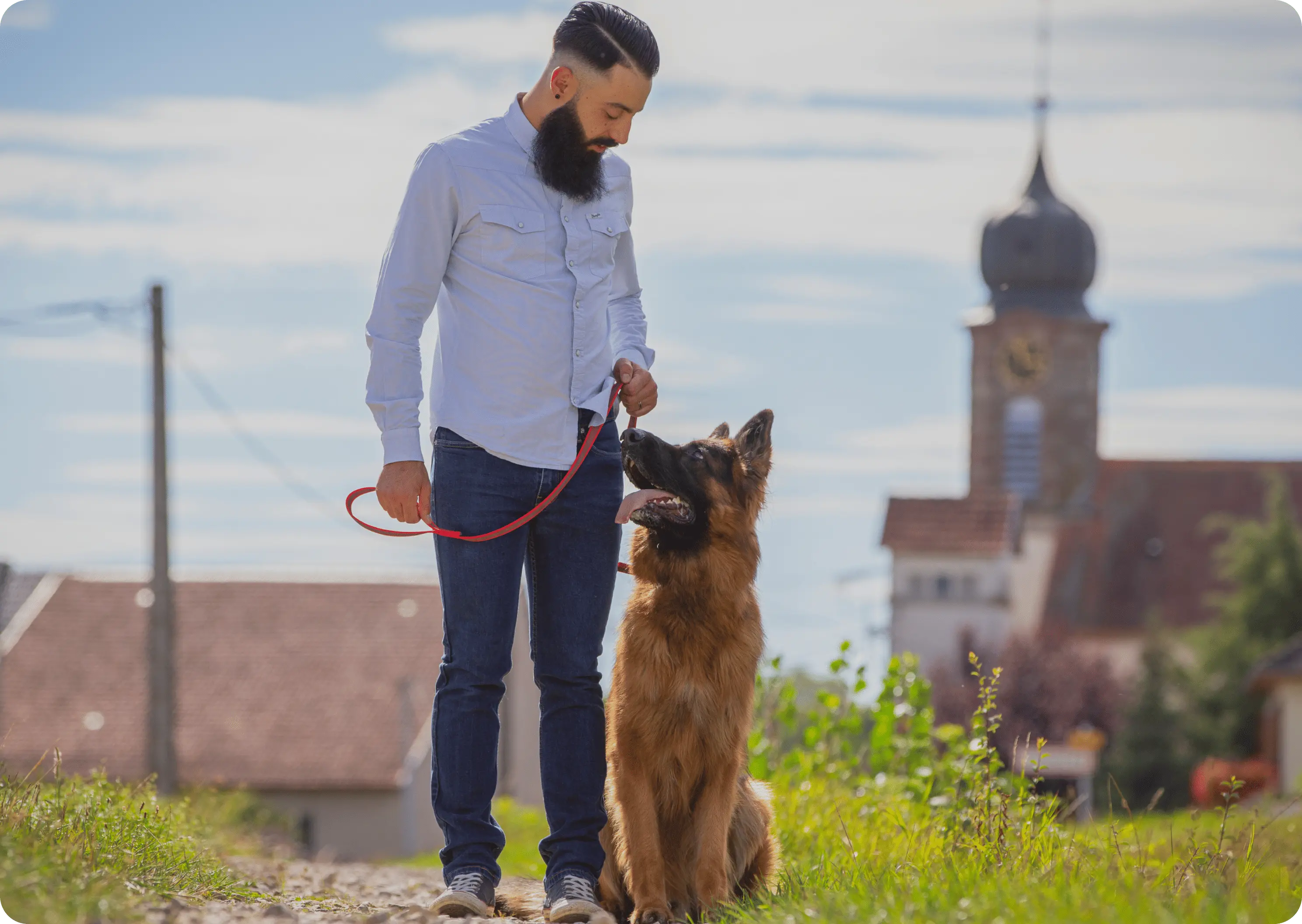 L'éducateur debout avec un Berger allemand en laisse dans un village luxembourgeois